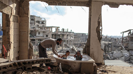 Pai dando banho em seus filhos, em sua casa destruida
